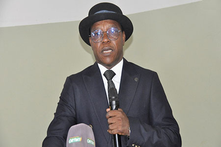 Le professeur Boubacar Sidiki Cissé s'exprimant lors d'une conférence, un microphone à la main.